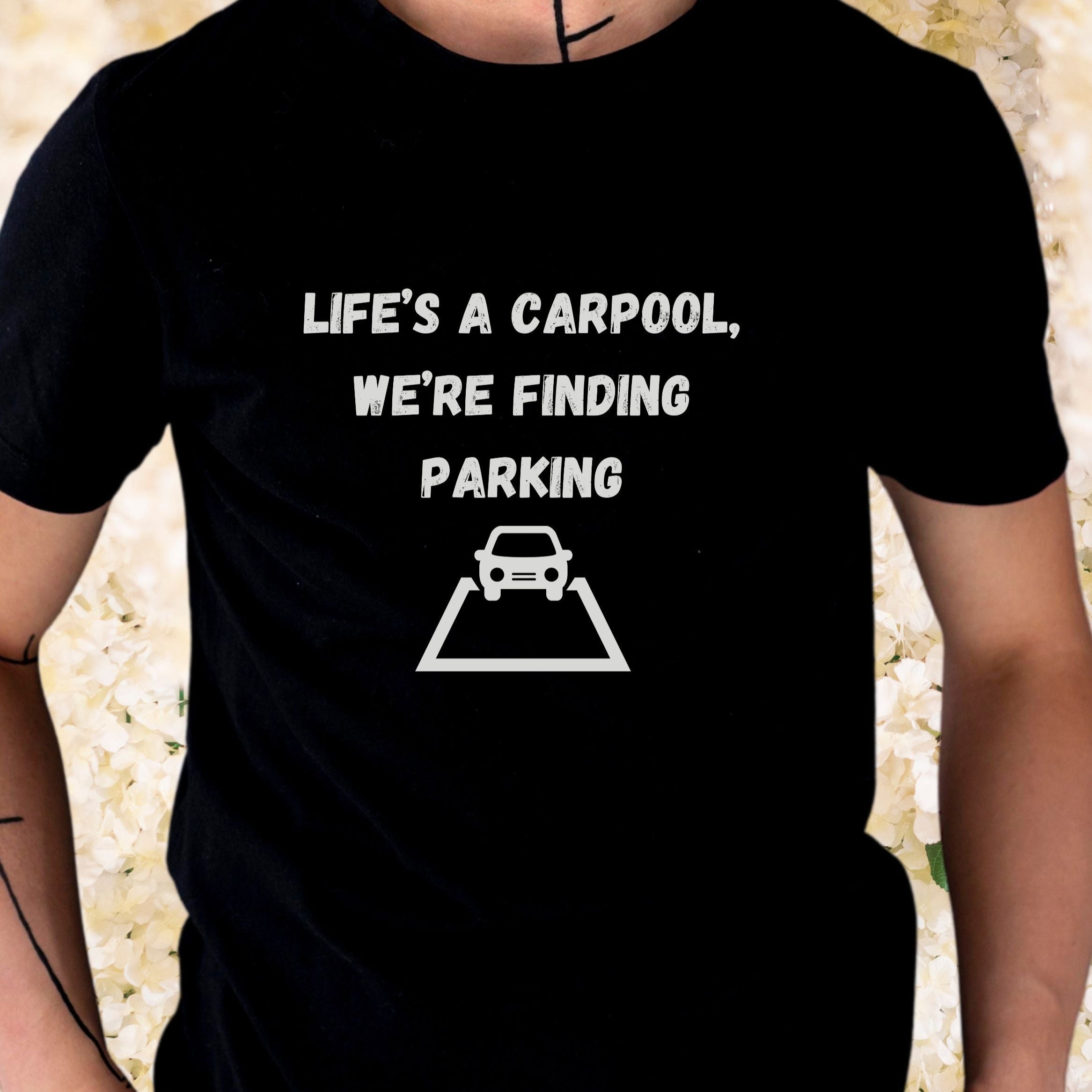 Black t-shirt with white text and graphic, worn by a person against a blurred background